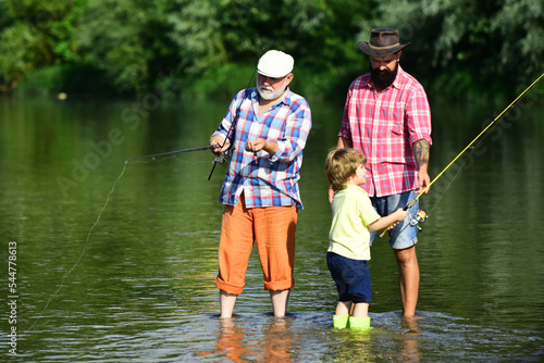Anglers. Fly fishing for trout. Father teaching son how to fly-fish in river. Grandfather and father with cute child boy are fishing.