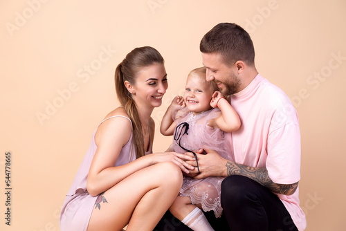 Portrait of nice family. Happy mom and dad hugs little cute daughter. Family look