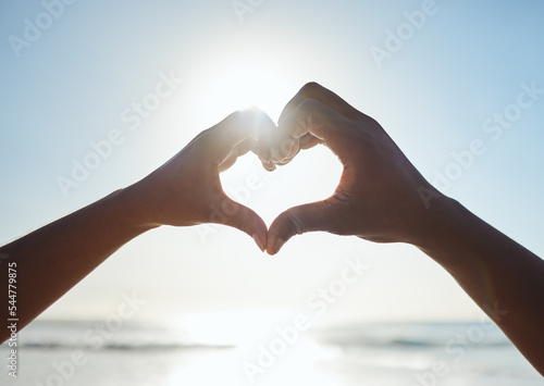 Heart  love and couple hands on beach with blue sky for summer  outdoor health and holiday for nature  earth day and travel. People with care sign together for ocean  sea and clean water with mock up