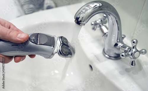 Bilde på lerret Cleaning the electric shaver under water in the faucet