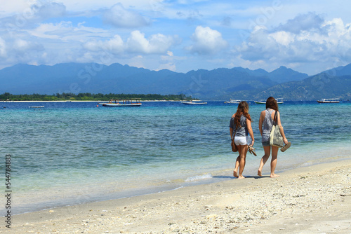 Two female tourists walking on the beach of Gili Trawangan.