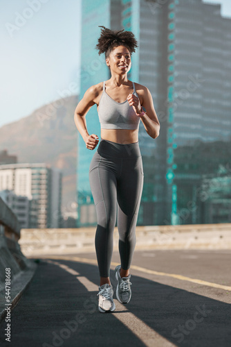 Running, fitness and city with a sports woman on a street for a cardio or endurance workout alone in the day. Health, training and exercise with a female athlete or runner on an asphalt road in town