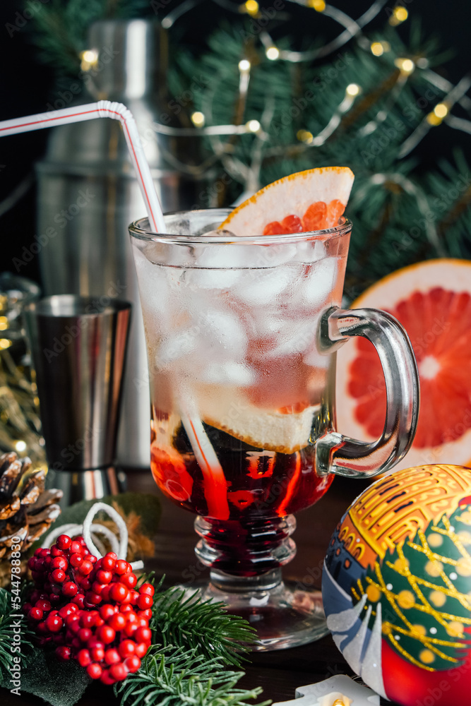 Christmas coctail drink with grapefruit ice and straw in glass mug at Christmas decoration. Selective focus Christmas coctail drink with grapefruit ice and straw in glass mug at Christmas decoration. Selective focus