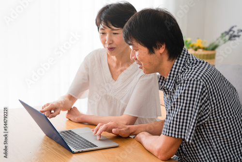 ノートパソコンを一緒に見るミドル男性とミドル女性 © aijiro