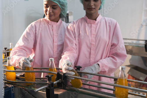 Asian woman factory worker or woman expert quality staff is checking bottles line for beverage