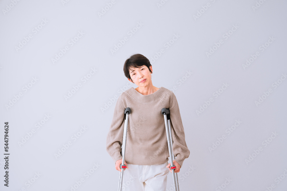 不安そうな表情をする松葉杖をついたミドル女性 医療保険イメージ 不安そうな表情をする松葉杖をついたミドル女性 医療保険イメージ