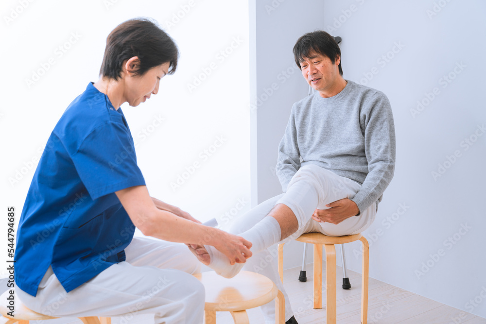 Obraz premium 医者に包帯を巻かれる中年男性 医療イメージ
