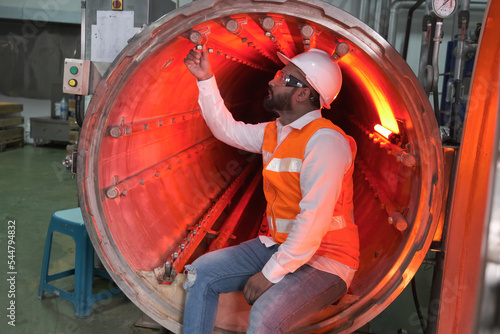 asian male factory worker or Man engineer or expert staff wear safety vest and helmet of maintenance and checking steam boiler