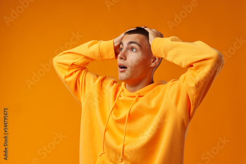 Young handsome man shocked with surprise expression standing over yellow background