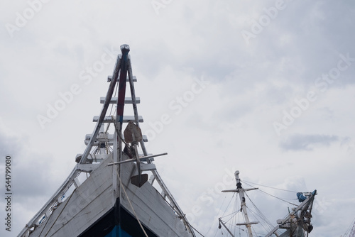 the front side of a large fishing boat moored in the harbor. anchor hanging, seen from below