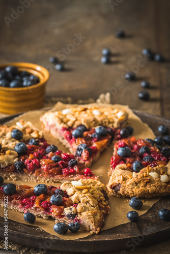 Pieces of a berry galette with fresh blueberries on a rustic wooden table  vertical