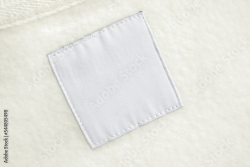 Blank white laundry care clothes label on fabric texture background