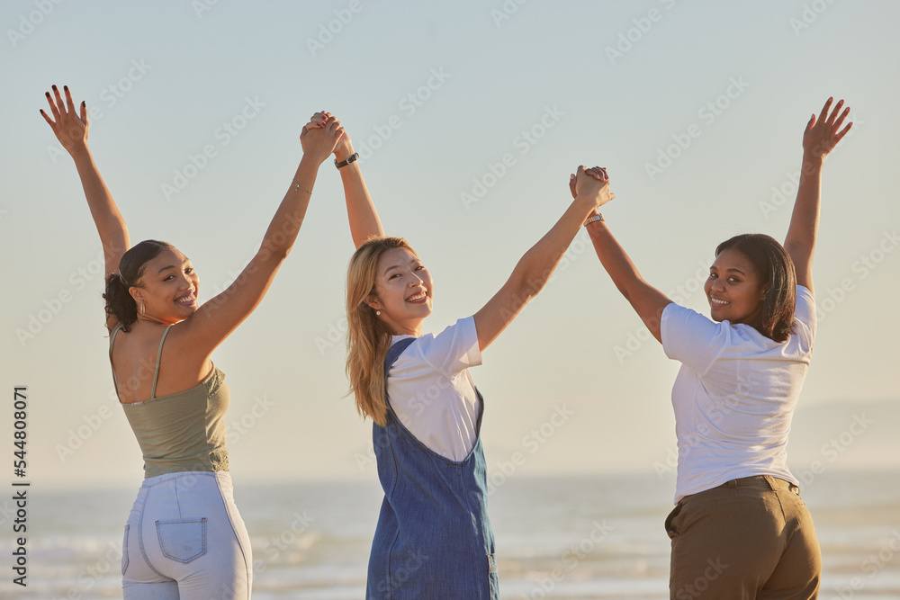 Happy, girl friends and holding hands at a beach with women on a holiday, freedom and travel. Portrait of people with arms raised to show excited adventure by the ocean and sea together by water Happy, girl friends and holding hands at a beach with women on a holiday, freedom and travel. Portrait of people with arms raised to show excited adventure by the ocean and sea together by water