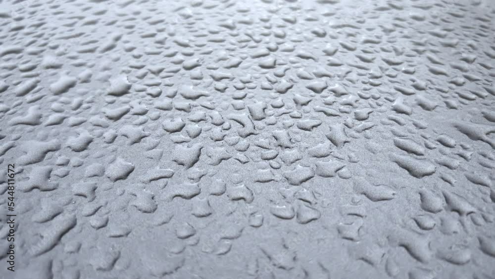 Drops on the hood of a car after rain. The camera gradually moves away from close-up to medium shot. Drops on the hood of a car after rain. The camera gradually moves away from close-up to medium shot.