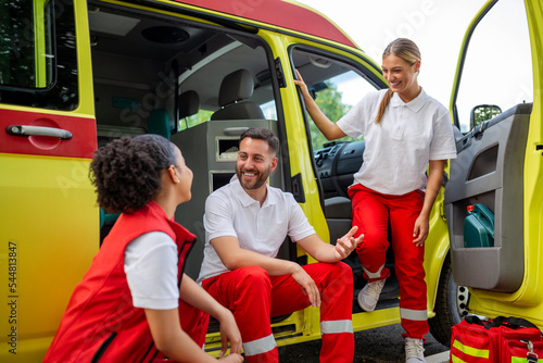 Multi-ethnic paramedics standing at the fromt of an ambulance. Emergency doctor and nurse standing in front of ambulance photo