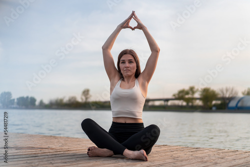 Young woman doing yoga by the lake