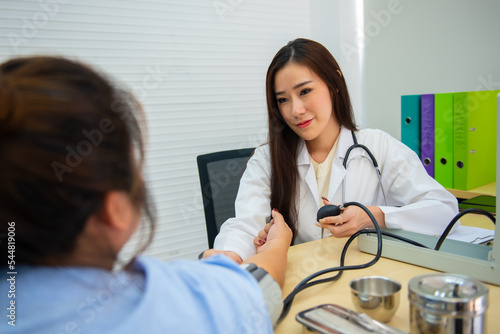 Asian female doctor use mercury blood pressure to determine patient blood pressure.