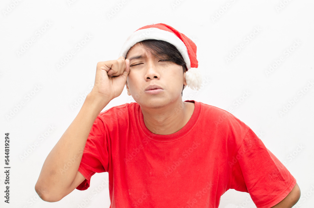 Sad attractive Asian man in red Christmas theme clothes isolated over white. christmas concept man in red santa claus clothes with sad expression wiping the tears. Sad attractive Asian man in red Christmas theme clothes isolated over white. christmas concept man in red santa claus clothes with sad expression wiping the tears.