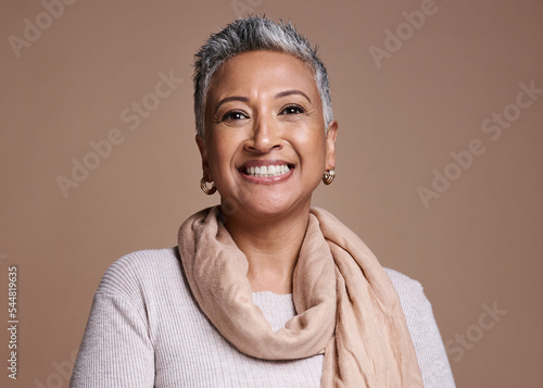 Face, fashion and beauty with a senior woman in studio on a brown background to promote contemporary style. Portait, fashionable and trendy with a mature female posing to model a clothes brand photo