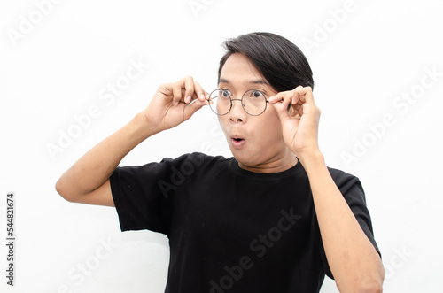 estactic attractive young asian man shocked happily opening mouth and lowering glasses. asian man with glasses feels shock with wow surprised expression.