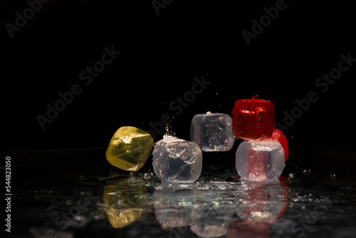 Falling colored cubes splashed with water on a black background. Red, yellow, blue and transparent. Conceptual, celebrated, commercial design