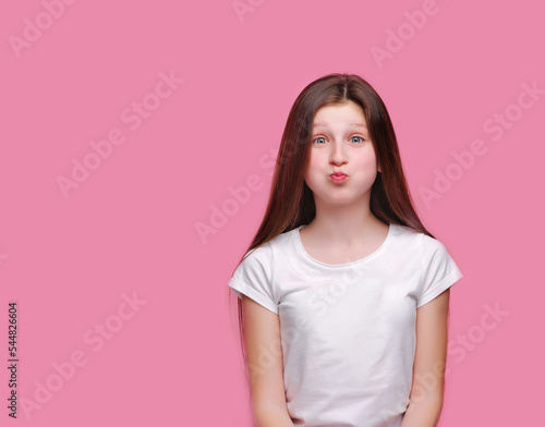 Funny teen brunette girl puffing out her cheeks against pink background