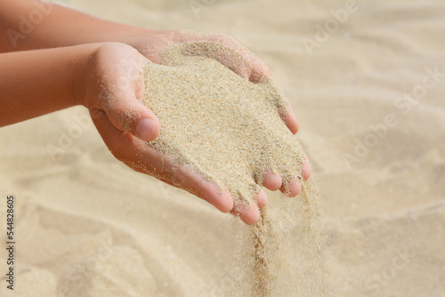 Canvas Print Child pouring sand from hands on beach, closeup