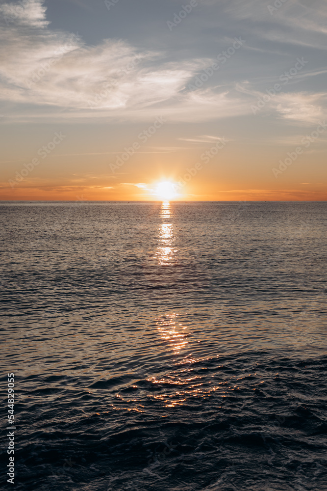 Calm sea with sunset sky and sun through the clouds over. Meditation sea and sky background.