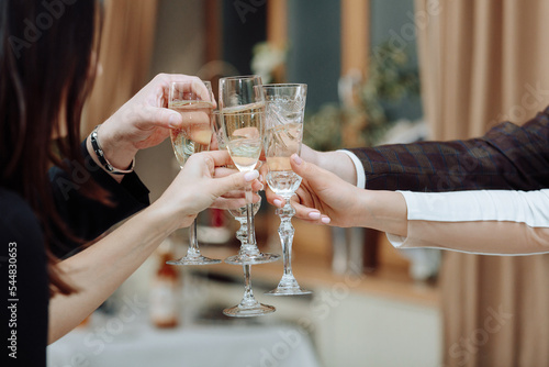 Friendly clinking of glasses after a toast. Celebration of a solemn event or holiday, birthday or wedding. photo