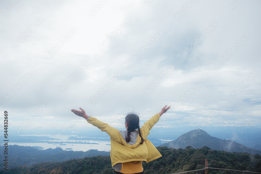 Woman standing on cliff and see over view in nature. Tourist show hands up and enjoying fresh air. Woman enjoying free happiness in beautiful Thailand landscape. Woman standing on cliff and see over view in nature. Tourist show hands up and enjoying fresh air. Woman enjoying free happiness in beautiful Thailand landscape.