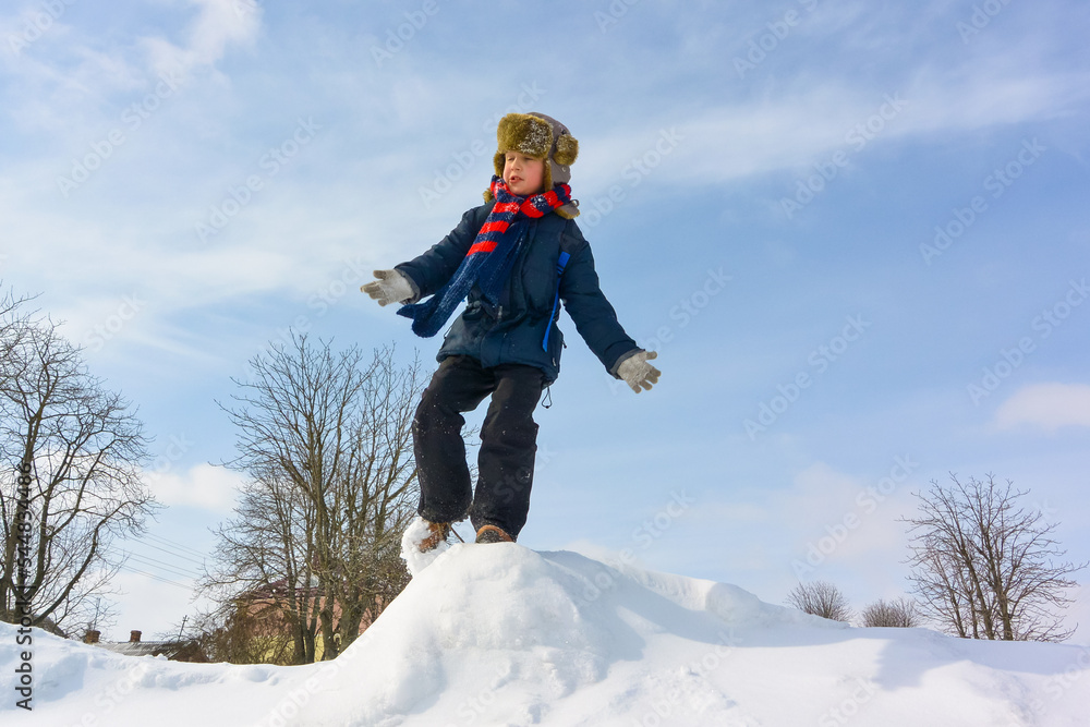 Boy, jumping, having fun on a snowy winter park. Happy boy outdoors. A boy plays outside in winter. Winter fun activity outdoor, winter vacation. Family time