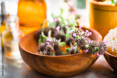 Wooden eco plate with pink flowers Wild Basil or Clinopodium vulgare of a medicinal plant collected during flowering in summer photo