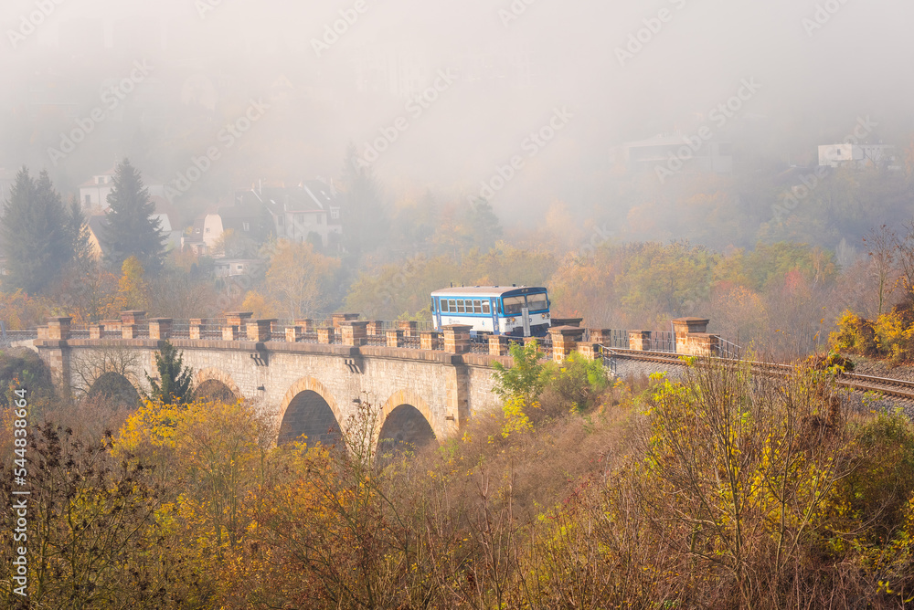 Photo of a train crossing a bridge. View of misty autumn on the railway of the Prague Semmering.