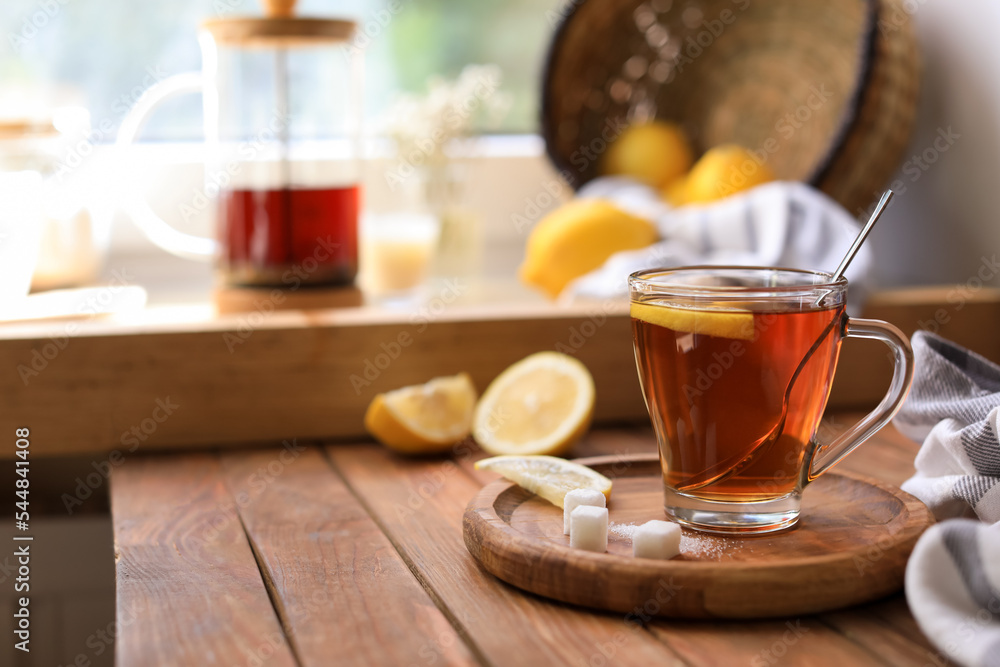 Glass cup with delicious tea, sugar and lemon on wooden table, space for text Glass cup with delicious tea, sugar and lemon on wooden table, space for text