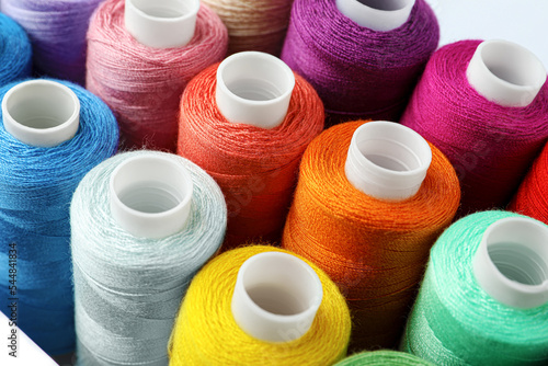 Set of different colorful sewing threads on white background, closeup