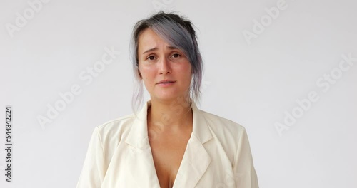 Pretty woman relives memories or hears something bad, suffers and is tormented, almost crying. Headshot footage of young Caucasian lady with dyed hair on white background