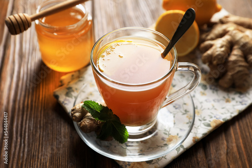 Cup of delicious ginger tea and ingredients on wooden table, closeup © New Africa