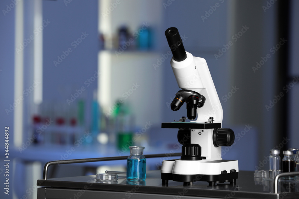 Modern medical microscope on metal table in laboratory, space for text Modern medical microscope on metal table in laboratory, space for text