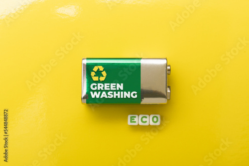 Greenwashing concept: battery on yellow background and die composing the word eco photo