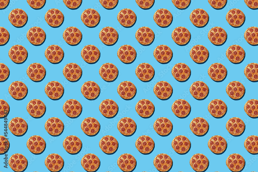 A hard light pattern of whole salami pizza pieces on a seamless bright blue background, top view