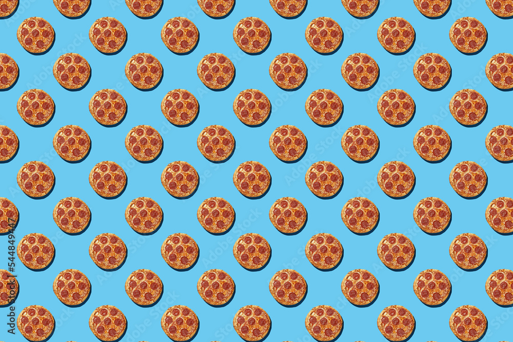 A hard light pattern of whole salami pizza pieces on a seamless bright blue background, top view A hard light pattern of whole salami pizza pieces on a seamless bright blue background, top view