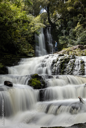 Man looking at the water flowing in waterfall in the middle of the rainforest