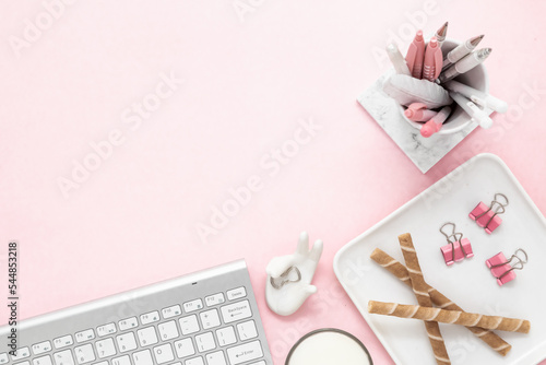 A feminine workspace, keyboard of computer on a pink background with copy space