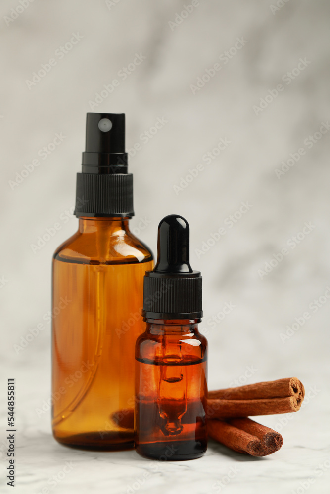Bottles of organic cosmetic products and cinnamon sticks on grey marbled background Bottles of organic cosmetic products and cinnamon sticks on grey marbled background