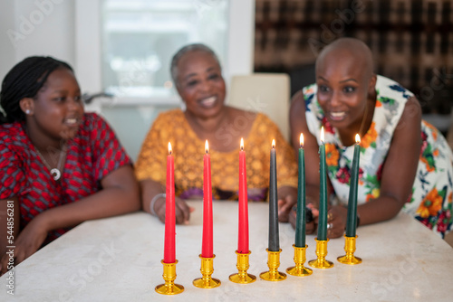 Teenage girl with mother and grandmother at table with Kwanzaa candles photo