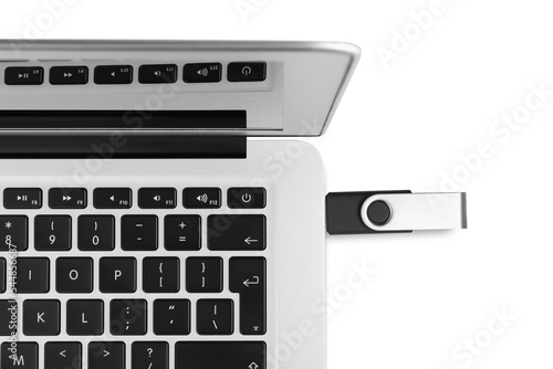 Modern usb flash drive attached into laptop on white background, top view photo