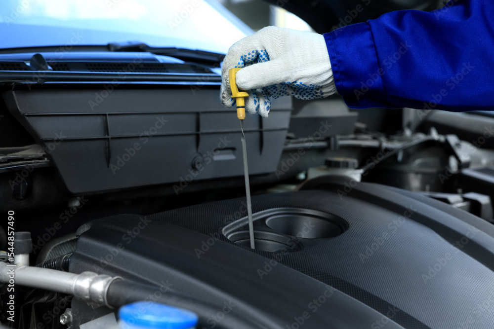 Worker checking motor oil level in car with dipstick, closeup - obrazy, fototapety, plakaty 