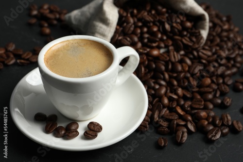 Cup of aromatic coffee and beans on grey table. Space for text