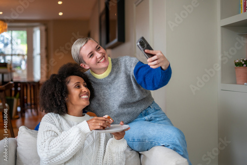 Smiling lesbian couple taking selfie at home