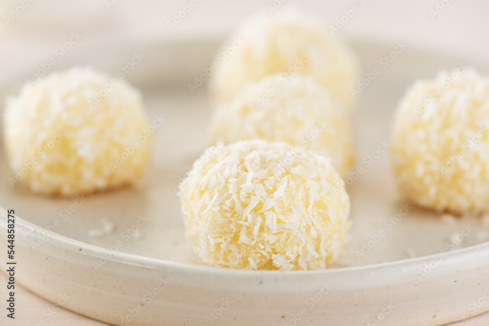 Dessert candy truffles with coconut on a plate, closeup. Dessert candy truffles with coconut on a plate, closeup.